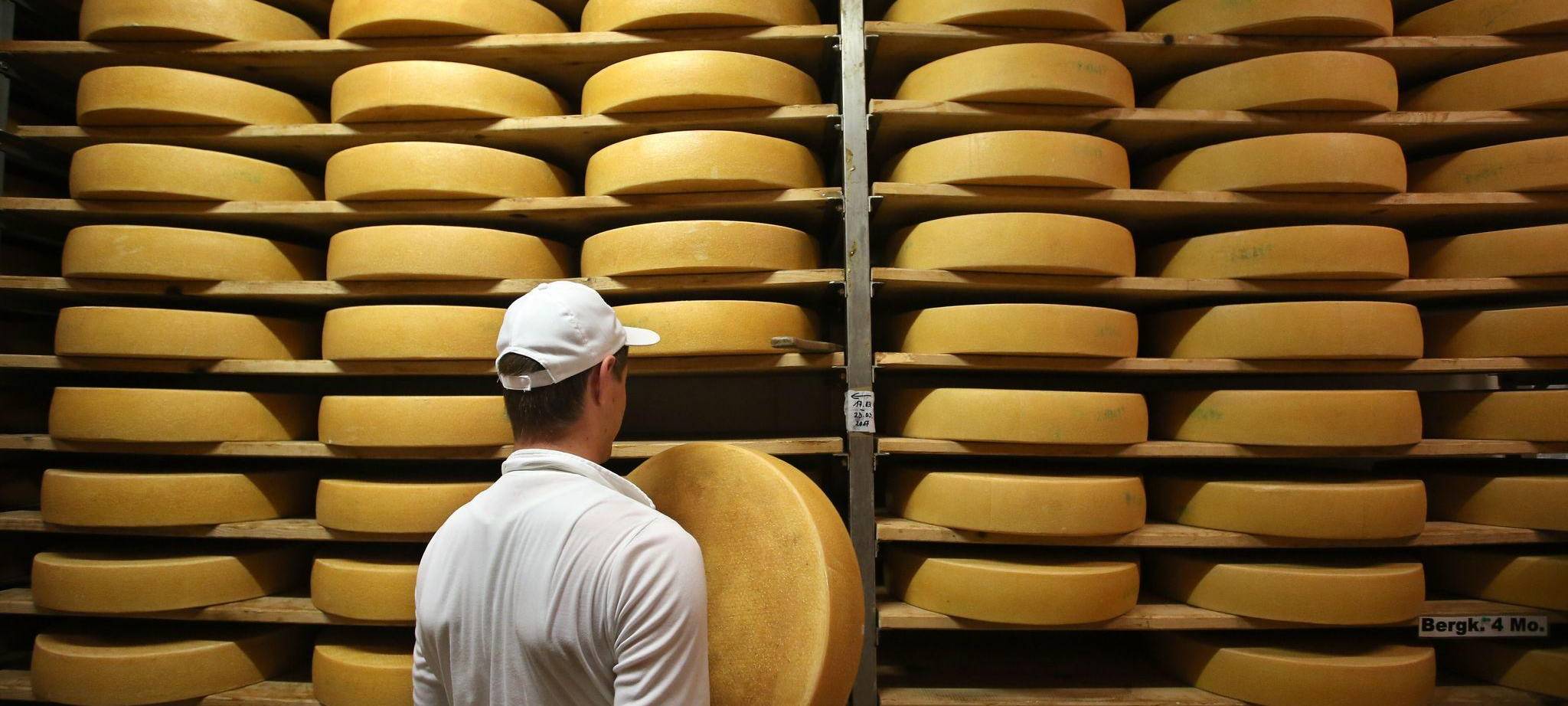 Sennerei-Mitarbeiter nimmt Allgäuer Bergkäse aus dem Regal
